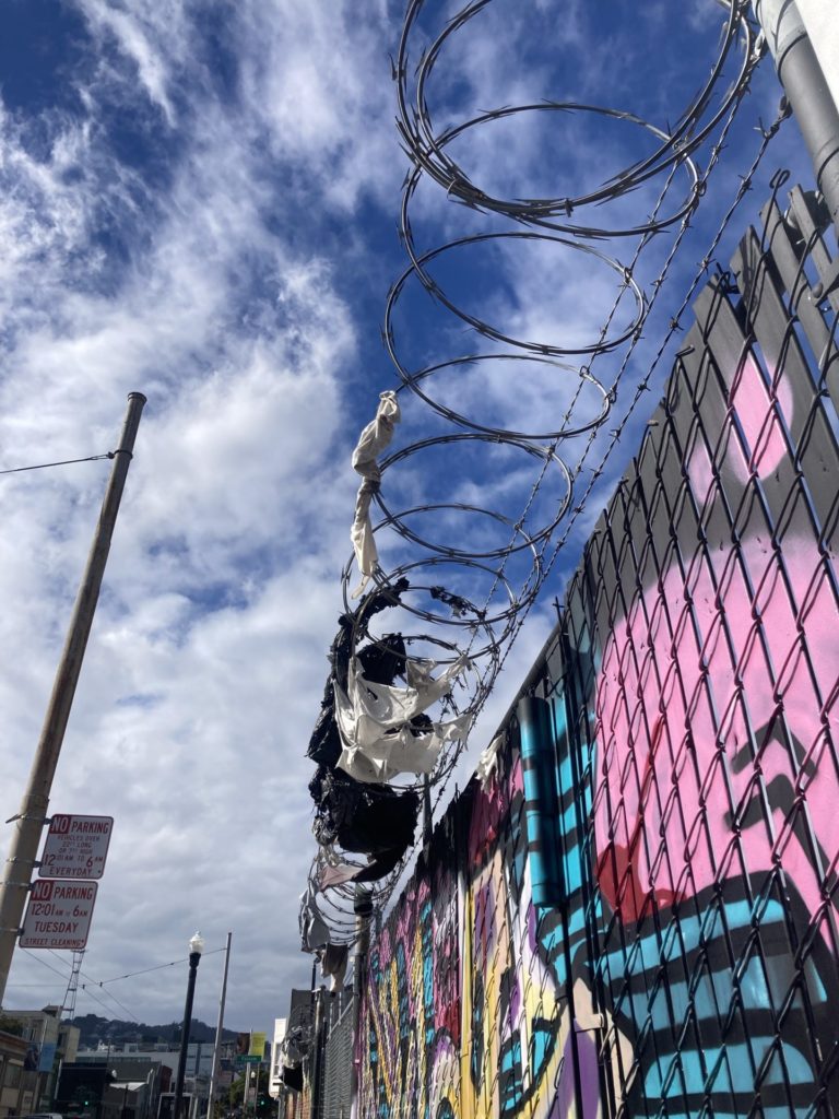 clothes and trash caught in razor wire above graffiti