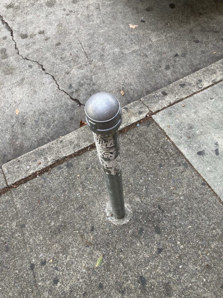 sidewalk with post that used to hold a parking meter