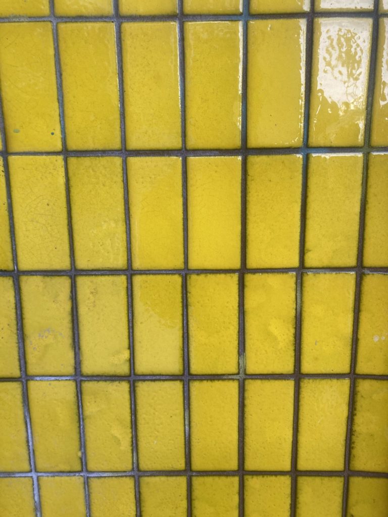 Rectangular, shiny bright yellow tile arranged in rows vertically.