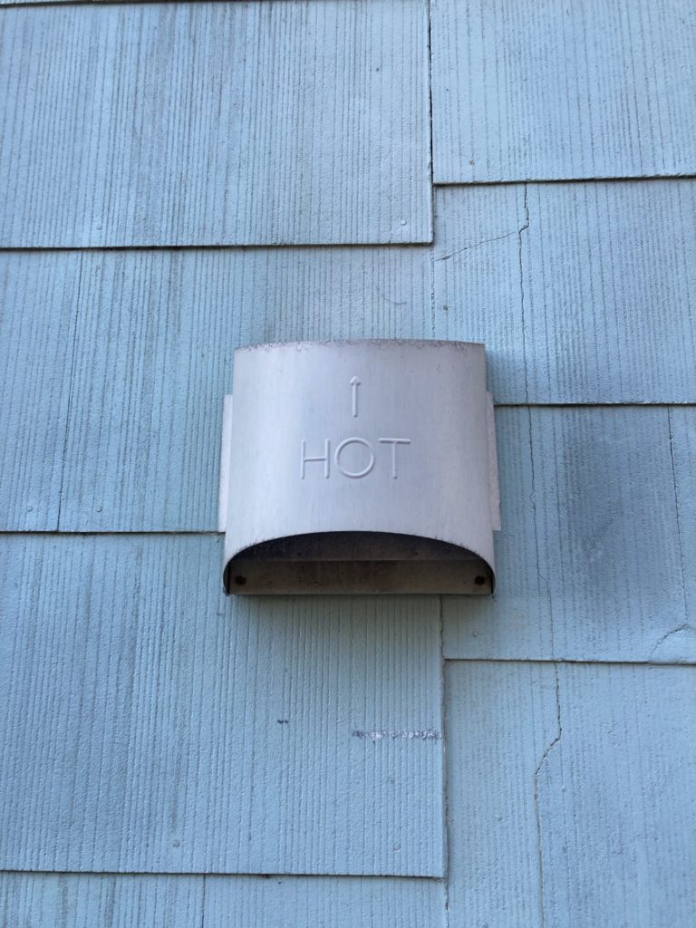 Old blue siding and a metal shield with an up arrow and the word “HOT”